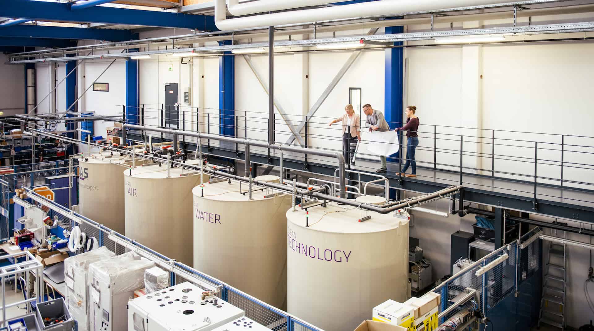 DAS Business unit waste water treatment three employees of DAS EE are looking at the manufacturing area of waste water treatment systems in DAS Headquarters